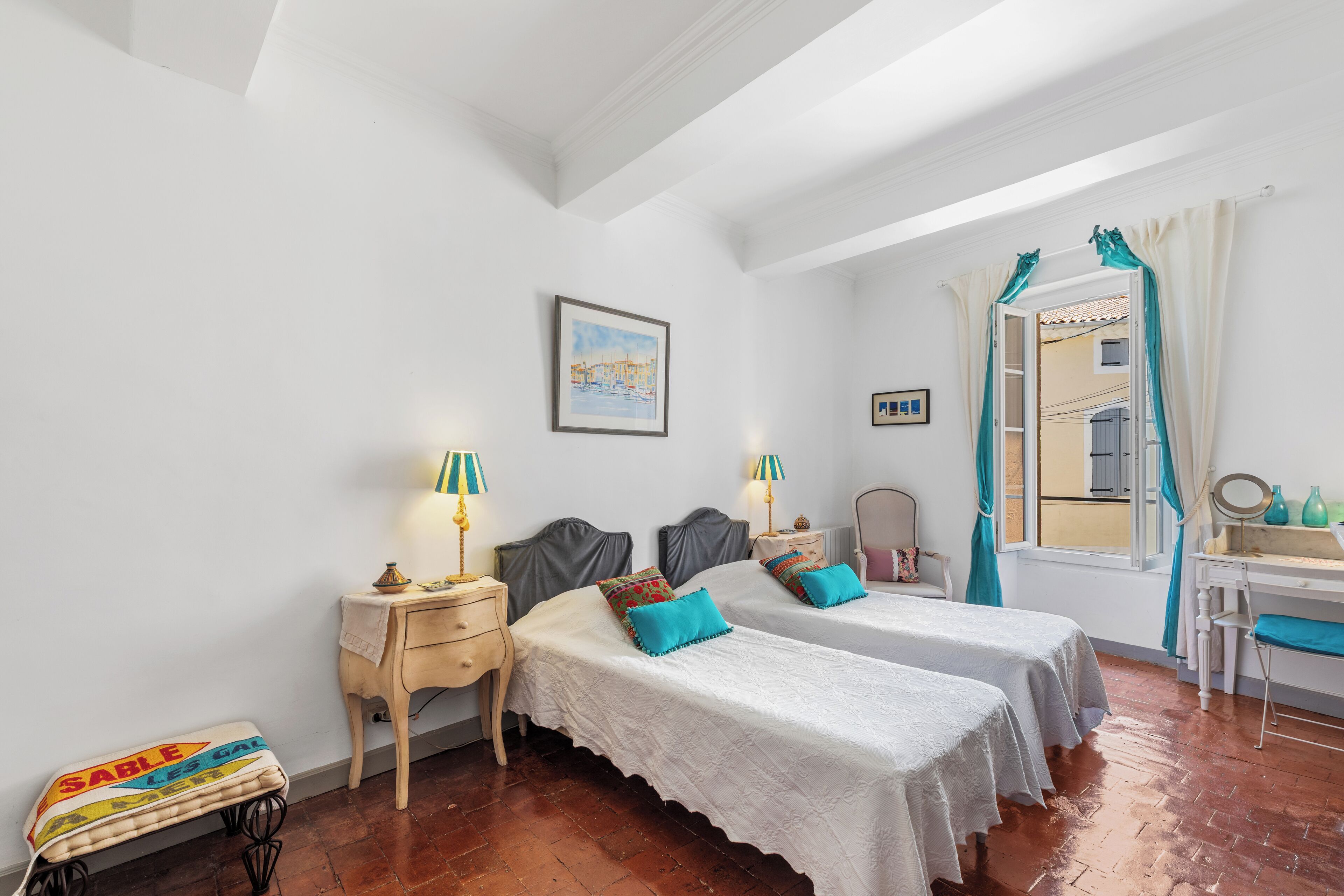 Une chambre avec deux lits, un bureau, une chaise et une fenêtre avec des rideaux.