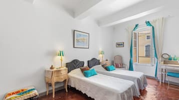Une chambre avec deux lits, un bureau, une chaise et une fenêtre avec des rideaux.
