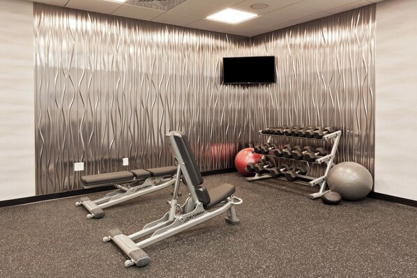 Un gimnasio con equipo de ejercicio, un televisor y una pared con un diseño ondulado.