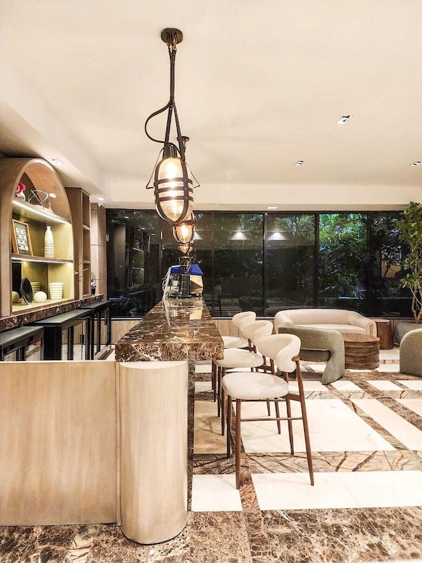 A modern kitchen with a marble countertop, bar seating, and a hanging light fixture. - Mauad Hotel Boutique & Spa, a member of Radisson Individuals (Santo Domingo)