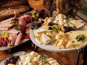Una tabla de quesos con distintos tipos de queso, uvas y hierbas aromáticas.