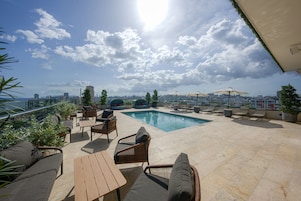 Una piscina al aire libre, sombrillas, sillones reclinables de piscina