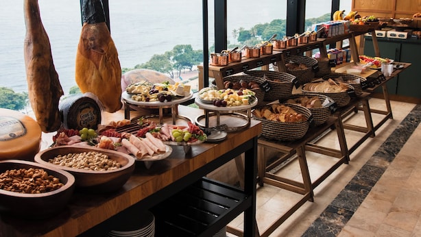 A buffet table with various food items and a view of the ocean. - Mauad Hotel Boutique (Santo Domingo)