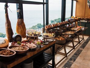Una mesa de buffet con diversos alimentos y vista al océano.