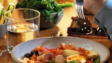 A dining table with a bowl of salad, a glass of water, and a fork.
