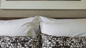 A hotel room with a bed, pillows, and a framed cityscape picture on the wall.