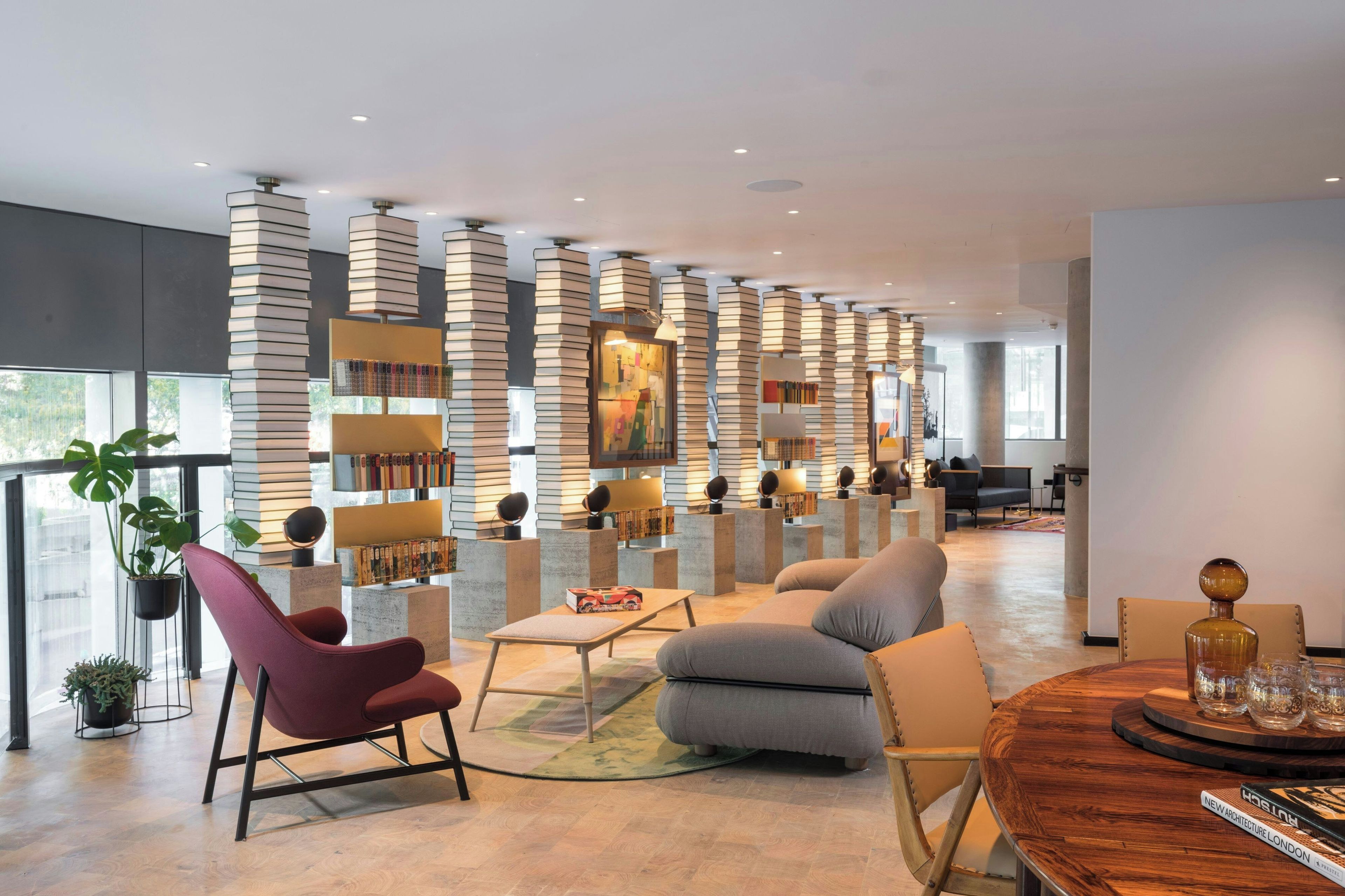 A modern interior with a seating area, bookshelves, and a large window.