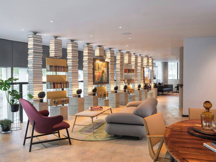 A modern interior with a seating area, bookshelves, and a large window.