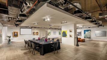 A conference room with a long table, chairs, and a projector screen.