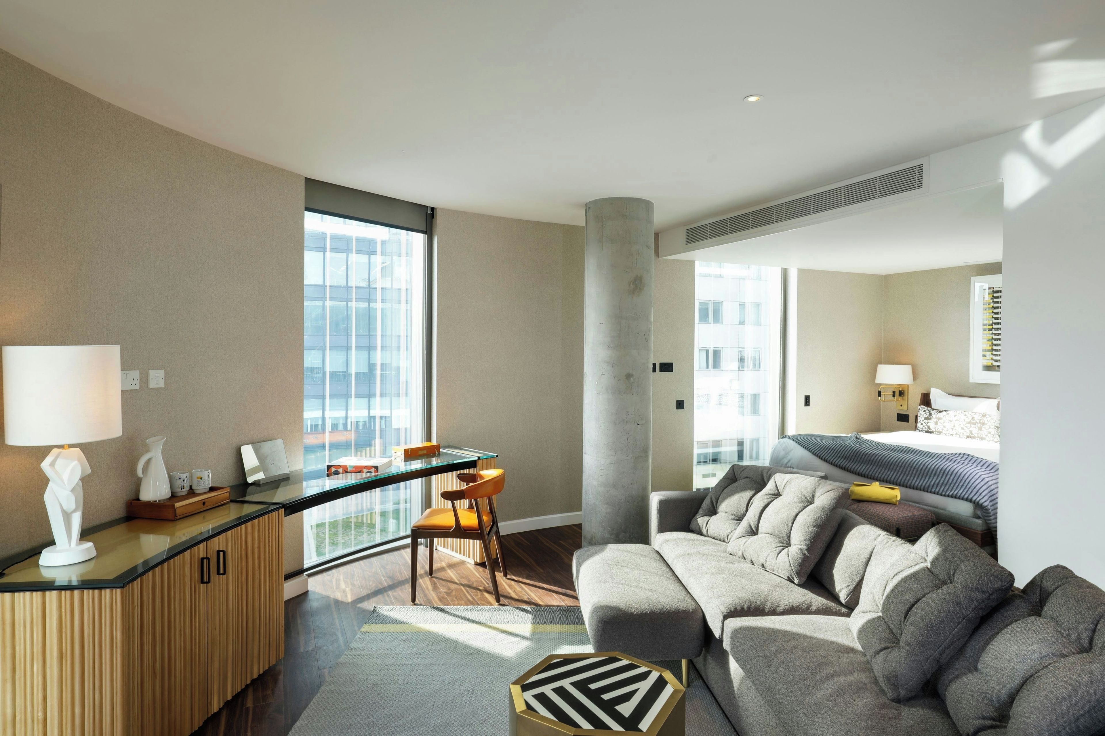 Ein modernes Hotelzimmer mit Balkon, einer Sitzecke, einem Schreibtisch und einem Bett.