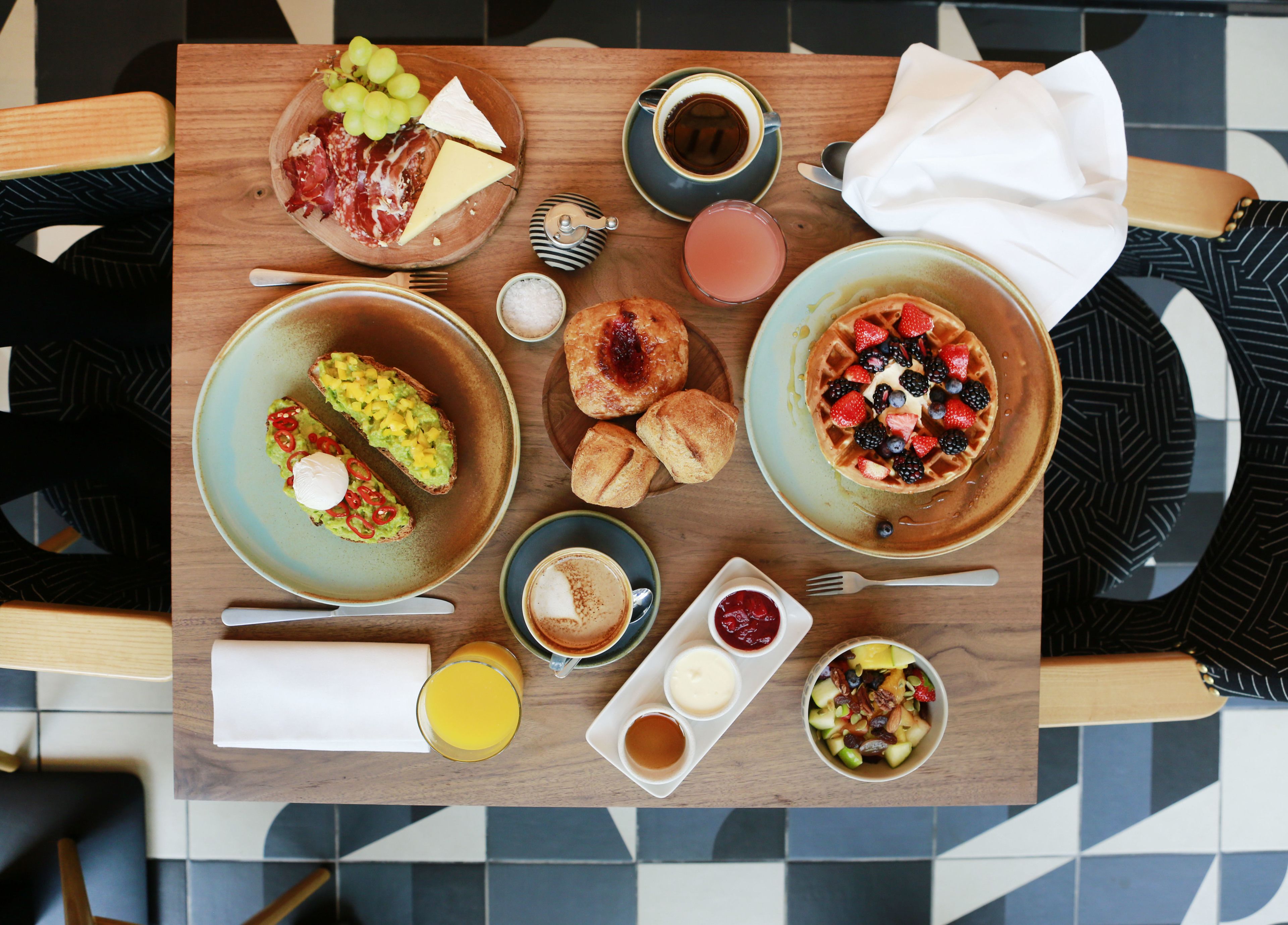 A breakfast buffet with various food items and drinks on a wooden table.