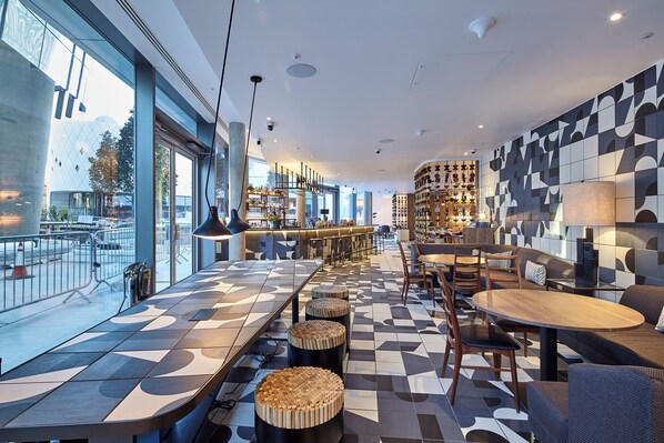 A modern bar area with a checkered floor, seating, and a bar counter. - Bankside Hotel, Autograph Collection (London)