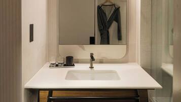 Un bagno moderno con uno specchio grande, un lavandino bianco e un mobile contenitore in legno.