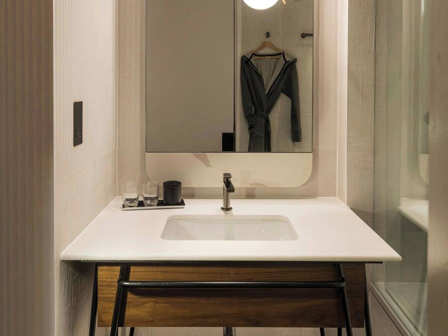Un bagno moderno con uno specchio grande, un lavandino bianco e un mobile contenitore in legno.