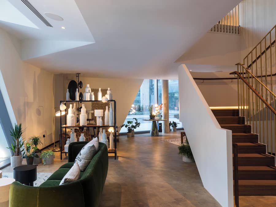 Et moderne interiør med en trappe, en grøn sofa og en udstilling af dekorative genstande.