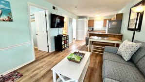 A compact living space with a kitchenette, a television, a sofa, and a coffee table. - Sunrise Ge 104 2 Bedroom Condo by RedAwning (Gulf Shores)