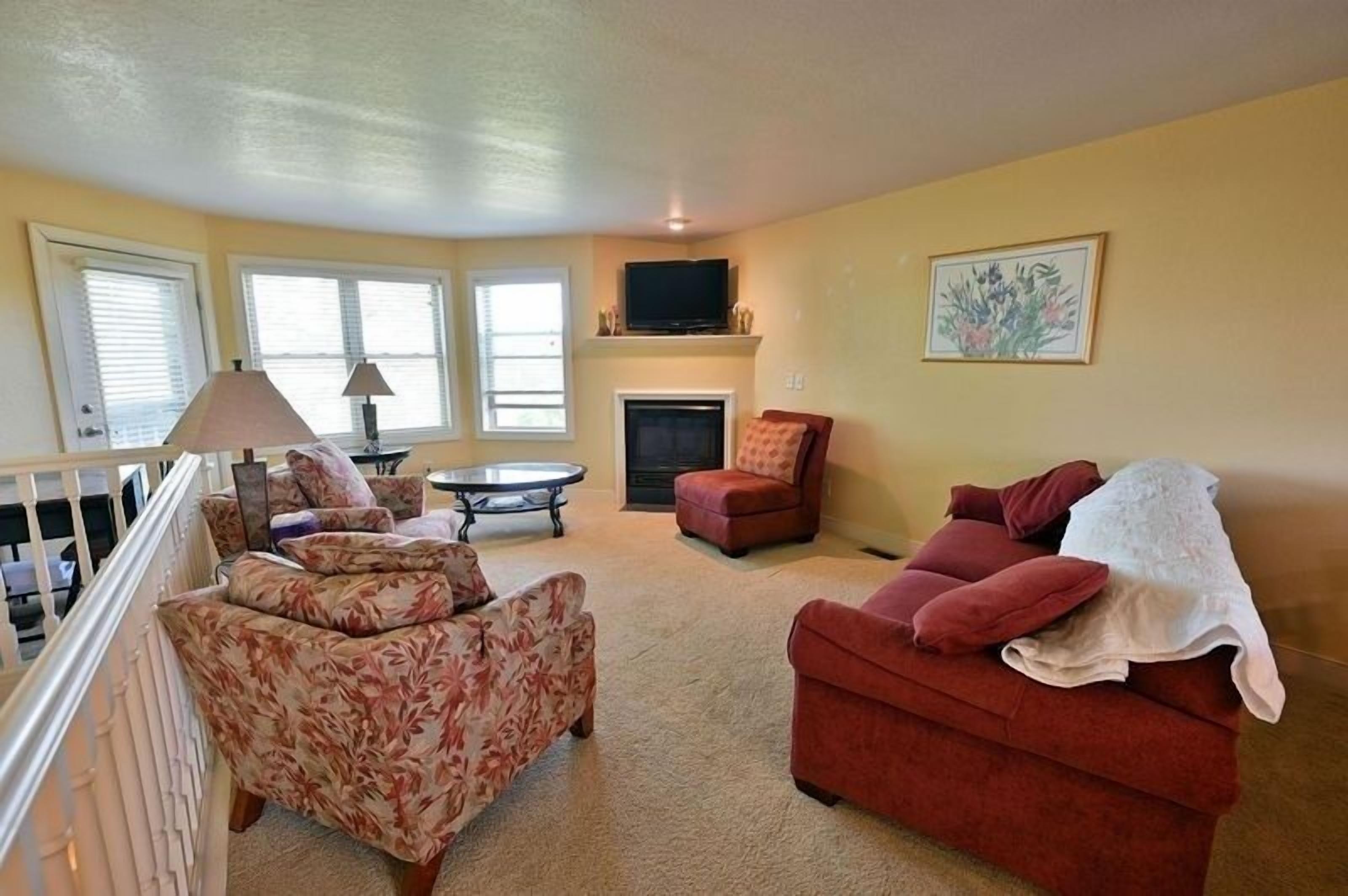 A living room with a fireplace, a television, and a painting on the wall.