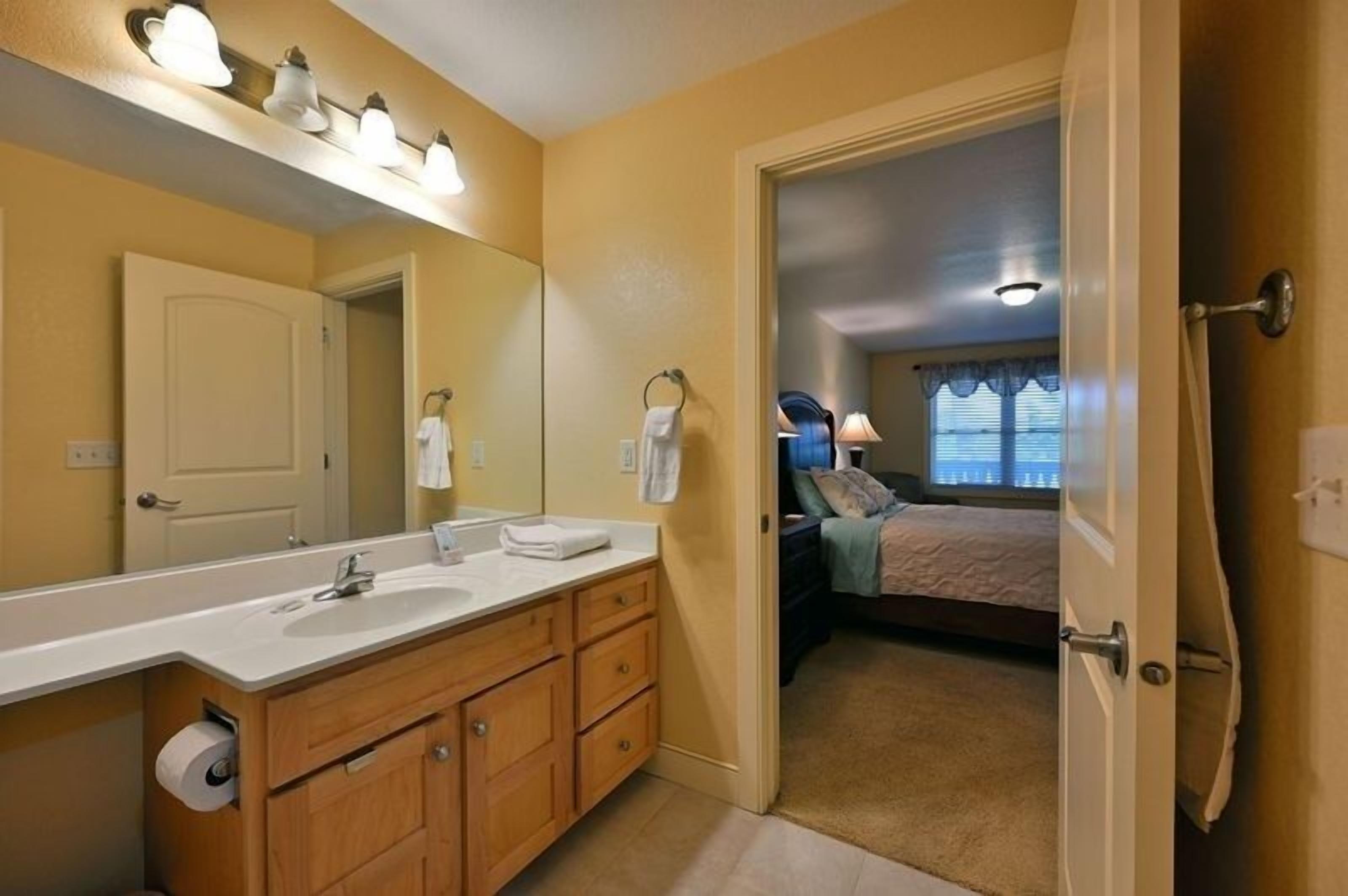 Un baño con tocador de madera, un espejo grande y un perchero para toallas.