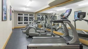 Un gimnasio con cintas de correr, elípticas y un espejo grande.