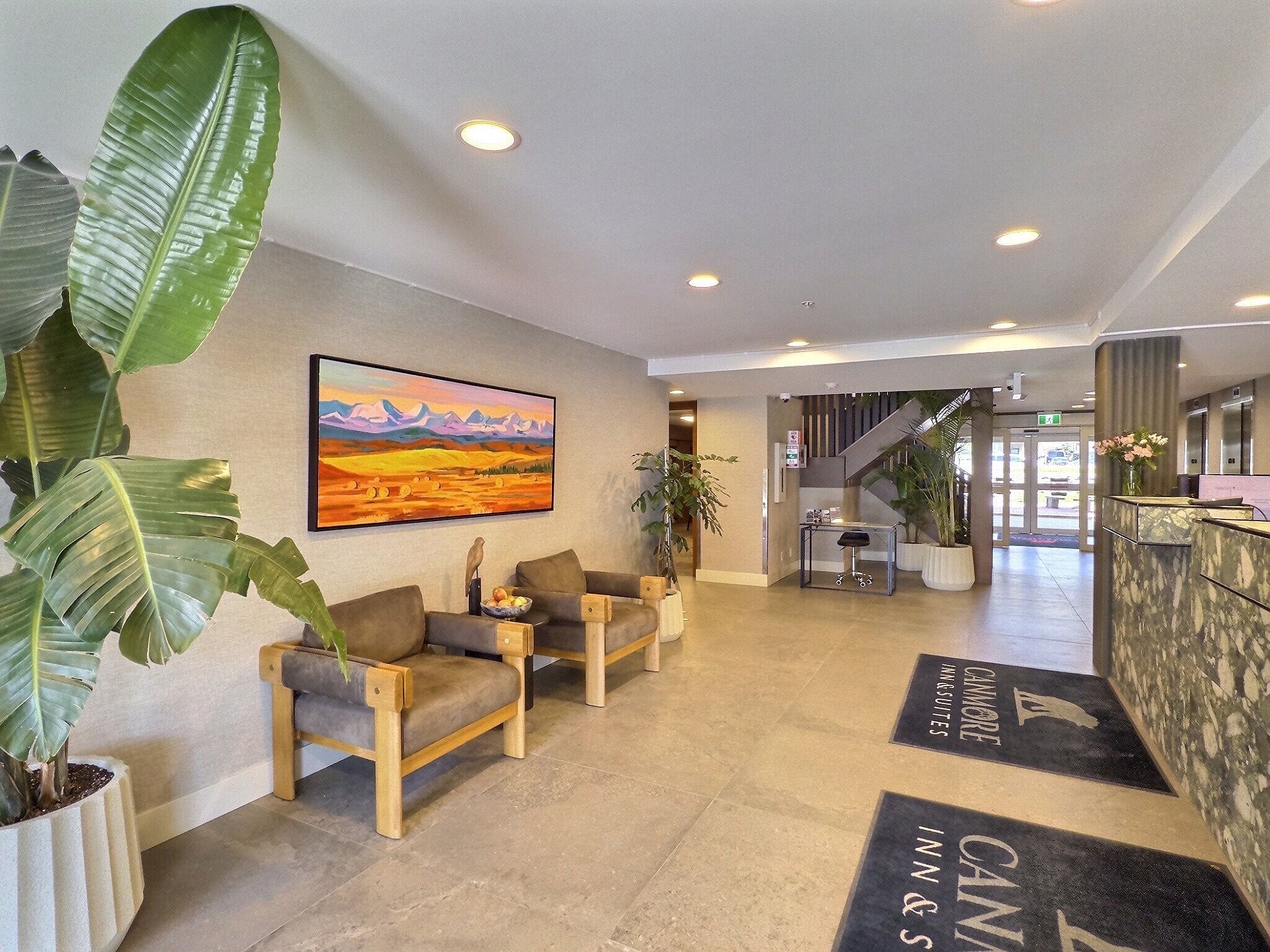 A hotel lobby with a reception desk, seating area, and a painting on the wall.