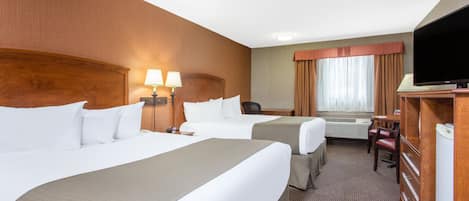 Une chambre d’hôtel avec deux lits, un bureau, une chaise, une télévision et une fenêtre avec des rideaux.
