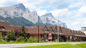 A hotel with a mountain backdrop, featuring a signboard with amenities like 'Inn & Suites' and 'Waterslide'.
