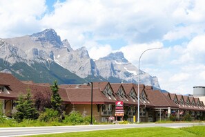 A hotel with a mountain backdrop, featuring a signboard with amenities like 'Inn & Suites' and 'Waterslide'.