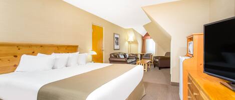 A hotel room with a large bed, a TV, a desk, and a sofa.