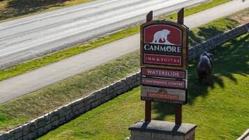 A sign for Canmore Inn & Suites Waterslide Conference Centre with a view of a road and mountains in the background.