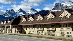 Una hilera de edificios de estilo chalet con balcones, con montañas nevadas al fondo.