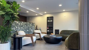 Un área de espera moderna con asientos, una mesa de centro y una estantería.