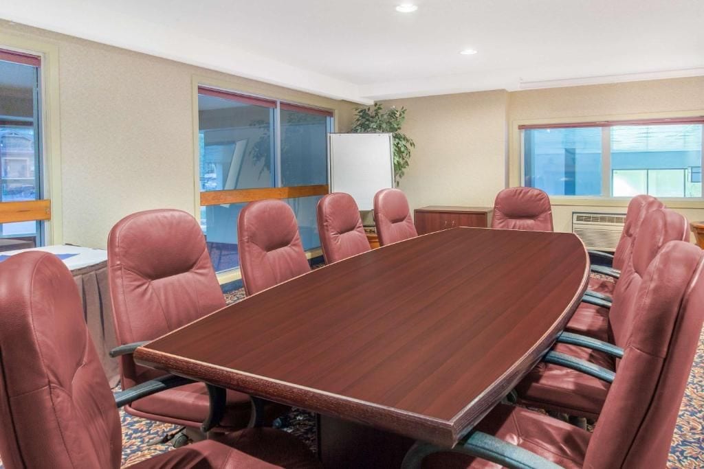 Uma sala de conferência com uma grande mesa de madeira e seis cadeiras estofadas.