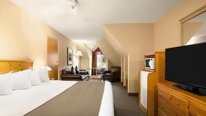 A hotel room with a large bed, a television, a desk, and a chair.