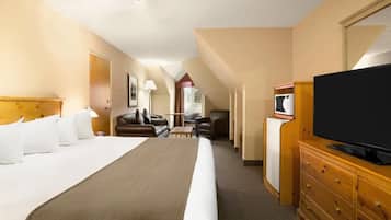 A hotel room with a large bed, a television, a desk, and a chair.