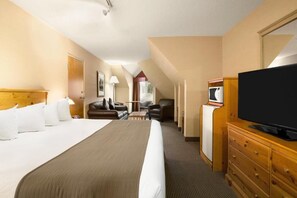 A hotel room with a large bed, a television, a desk, and a chair.
