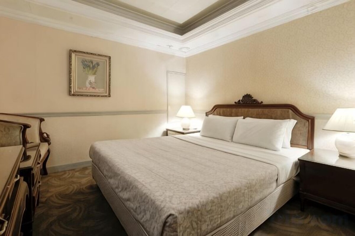 Habitación de hotel con una cama grande, mesitas de noche, un escritorio y una silla.