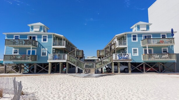 Un hôtel situé en bord de mer, doté de nombreux balcons et donnant sur une plage de sable.