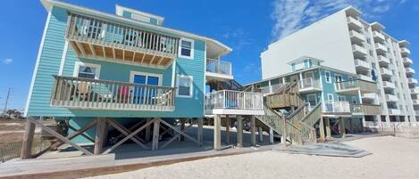 A beachfront hotel with multiple levels, wooden walkways, and a sandy beach area.