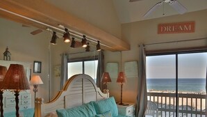 A bedroom with a bed, bedside lamps, a ceiling fan, a view of the beach, and a 'DREAM' sign on the wall. - Ocean Reef 702 3 Bedroom Townhouse by RedAwning (Gulf Shores)
