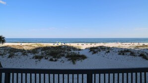 A beach with a clear sky, sandy shore, and a wooden railing in the foreground. - Ocean Reef 702 3 Bedroom Townhouse by RedAwning (Gulf Shores)
