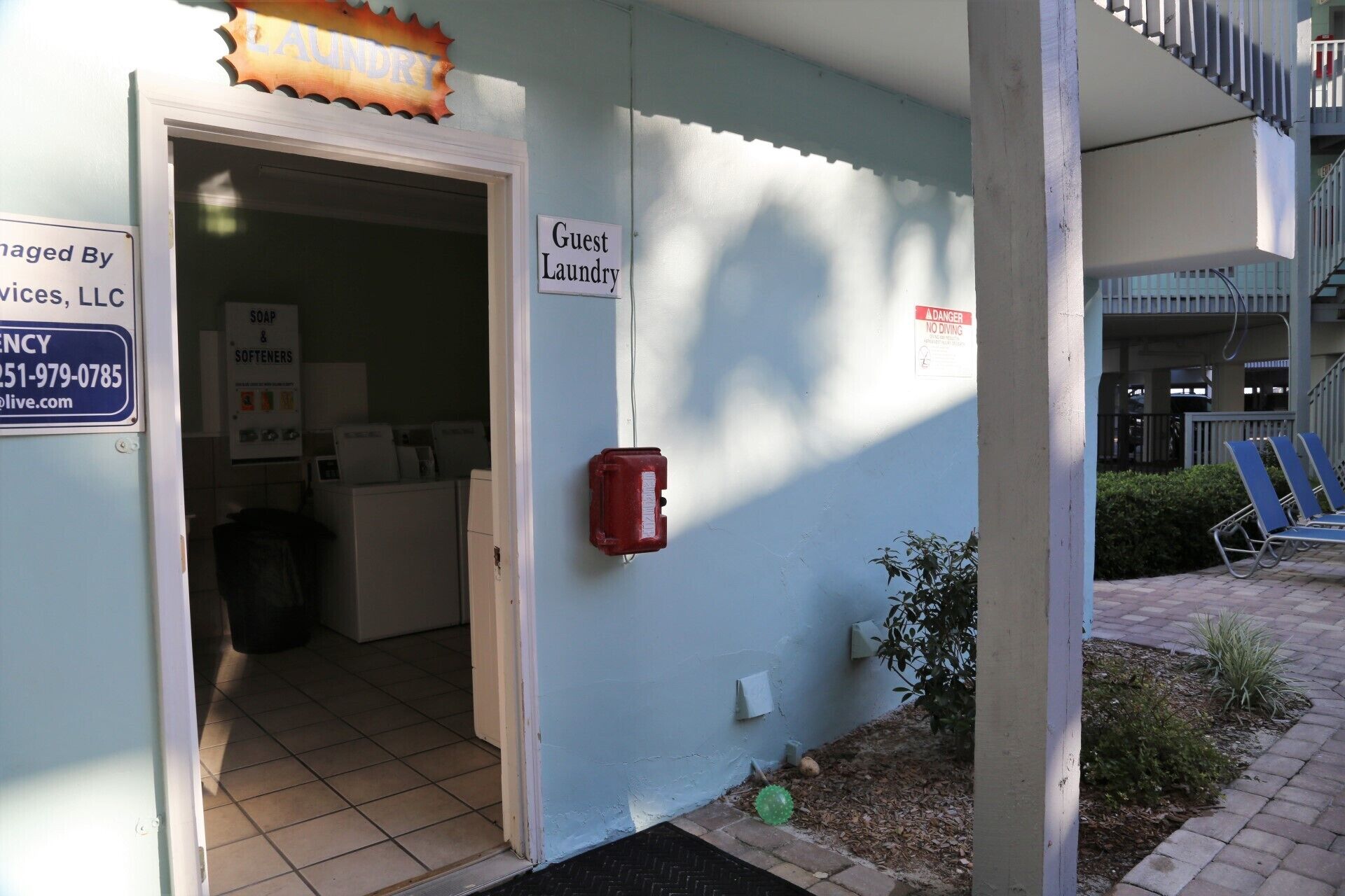 A guest laundry area with a sign indicating it's for guests, a red fire alarm box, and a sign for soap and softeners.