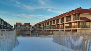 A hotel with multiple floors, balconies, and a sandy ground area. - Gulfside Townhome 13 2 Bedroom Townhouse by RedAwning (Gulf Shores)