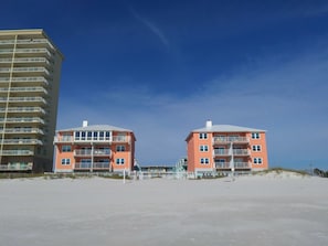A beachfront hotel with two pink buildings, a tall beige building, and a sandy beach. - Harbor House B2 2 Bedroom Condo by RedAwning (Gulf Shores)