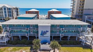 A hotel with a central building featuring balconies and a sign reading "Harbor House 913 W Beach Blvd". - Harbor House B2 2 Bedroom Condo by RedAwning (Gulf Shores)