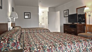 A hotel room with a large bed, a TV, a dresser, and a mirror.