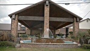 A covered outdoor area with a brick structure, a small pool, and a fountain.