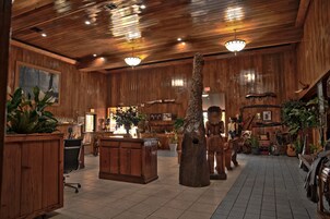 A rustic interior with wooden walls, a central wooden tree sculpture, and various decorative items.