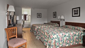 A hotel room with a bed, two bedside tables, a chair, a desk with a lamp, and a mirror.