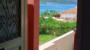 Vista desde un balcón con una reja de metal, un muro blanco y un seto verde.