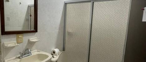 A bathroom with a sink, toilet, and a shower enclosure.